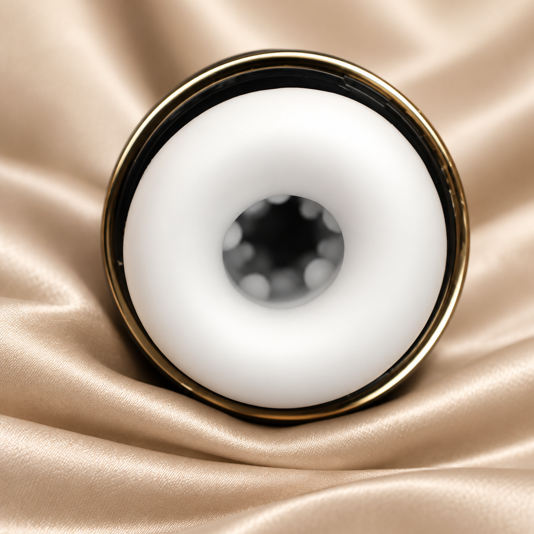 A close-up studio shot of a white circular ring-shaped product with a gold-toned rim, placed on draped champagne satin fabric.