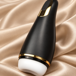 A sleek black personal massager with gold trim and a white silicone head, resting on a draped champagne satin fabric background.