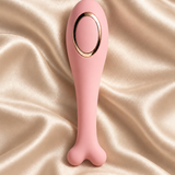 A pink silicone personal massager with a bone-shaped handle and a gold metallic oval accent, displayed on a draped champagne satin fabric background.
