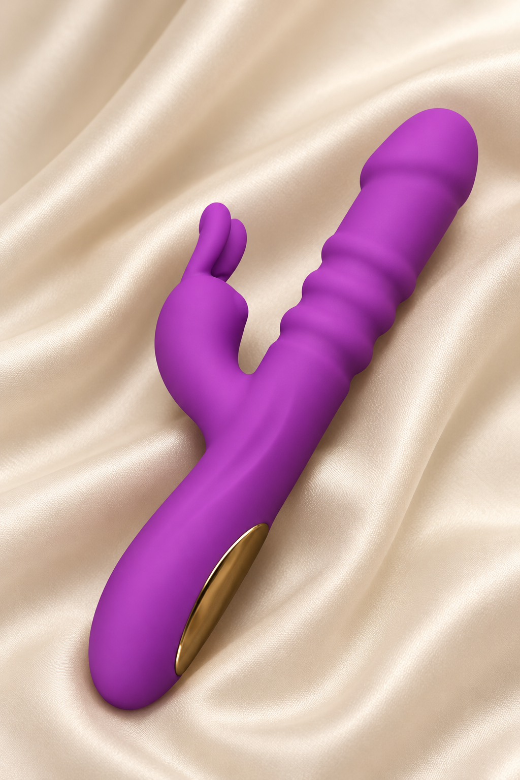 A purple dual-stimulation personal massager with a gold accent button, resting on a draped beige satin fabric background.