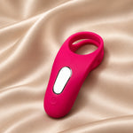 A bright pink personal massager with a sleek ergonomic design, a central white oval button, and a ring-shaped head, resting on a draped beige satin fabric background.