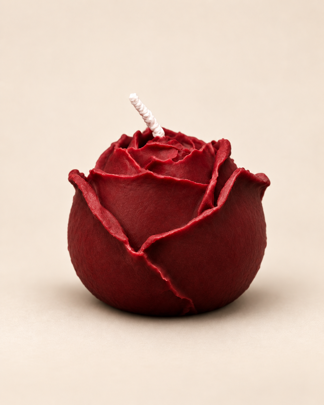 The Rose soy candle in burgundy on a warm beige background.